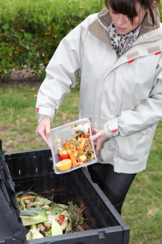 woman emptying vegetable scraps into compost bin